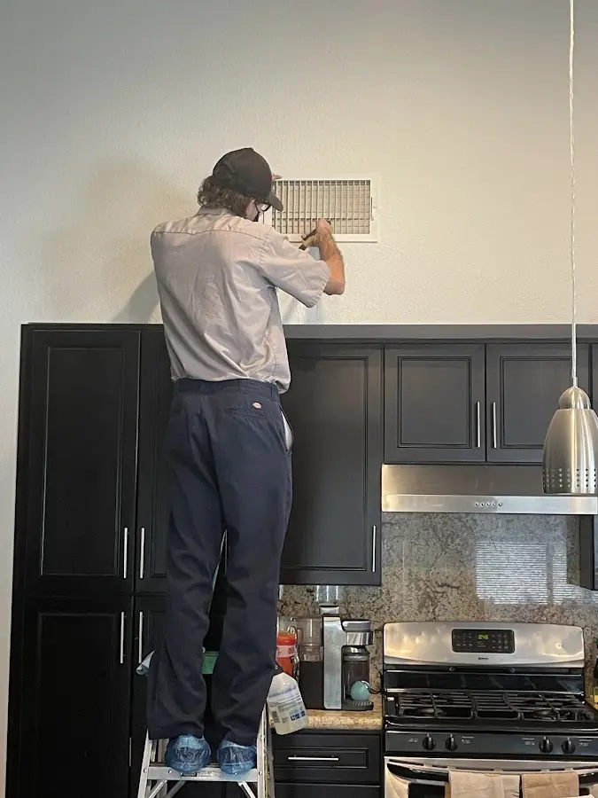 Technician inspecting an air vent during HVAC service in Ville Platte